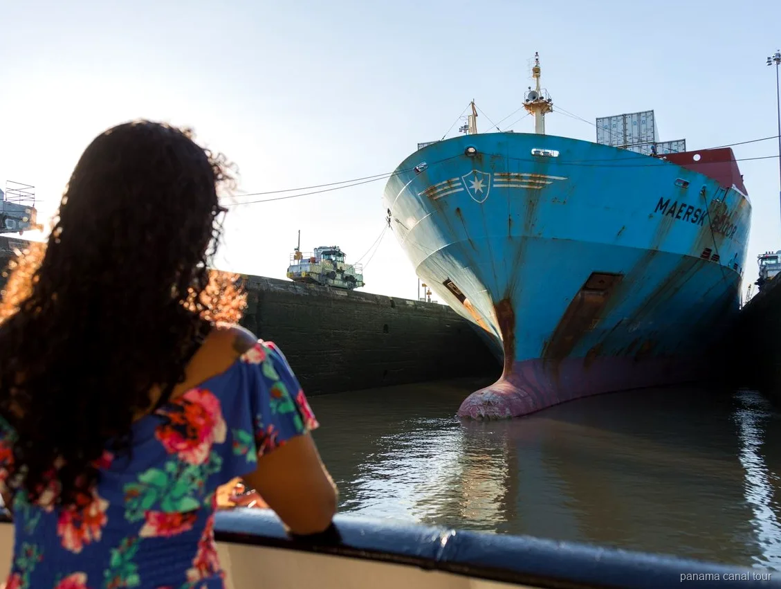 Frachtschiff bei der gemeinsamen Durchfahrt des Panamakanals mit dem Tourboot